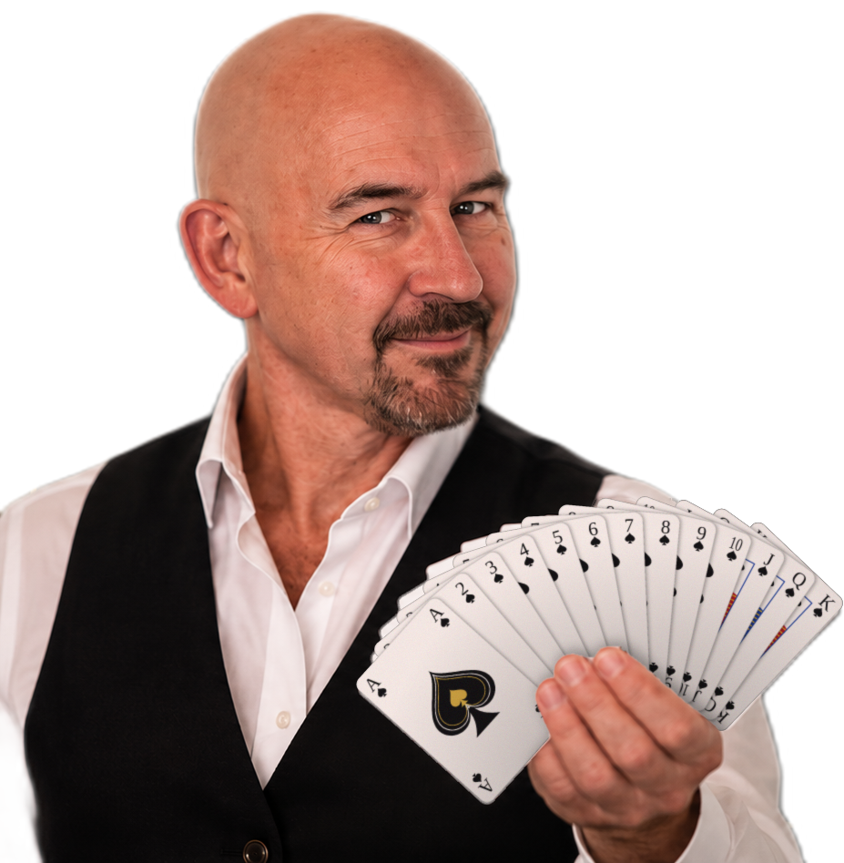 Robin Croft smiling and holding a fanned deck of playing cards, ace of spades at the front